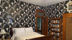 A bedroom with a bed, a nightstand, a lamp, a bookshelf, and a door. - Historic home in the heart of Poplar Bluff (Poplar Bluff)
