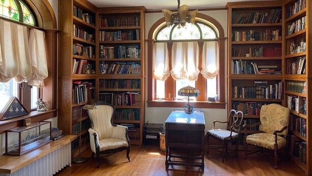 A library with wooden bookshelves, a table, and two chairs. - Historic home in the heart of Poplar Bluff (Poplar Bluff)