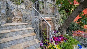 Eine steinerne Treppe mit Metallgeländern, die zu einer Steinmauer mit einer dekorativen Löwenstatue führt.
