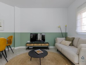 A living room with a sofa, a coffee table, a TV, and a dining area with chairs. - Evergreen Centre Apartment Living4malaga (Málaga)