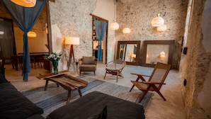 A cozy room with rustic stone walls, wooden furniture, and hanging lamps. - Casa Mandarina, 4BDR by Cercana (Mérida)