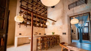 A rustic interior with exposed brick walls, wooden beams, a bar area with stools, and pendant lighting. - Casa Mandarina, 4BDR by Cercana (Mérida)
