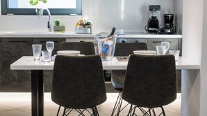 A modern kitchen with a dining area, featuring a white countertop, dark chairs, and a glass pitcher on the table.