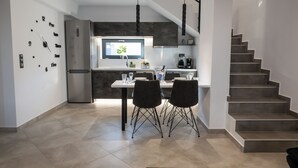 A modern kitchen with a dining area, a built-in clock, and a staircase.