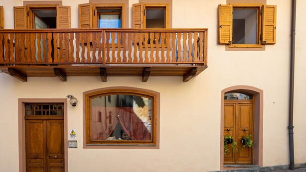 A building with a wooden balcony, a large arched window, and a double wooden door. - Nice apartment for 4 people with WIFI, TV and pets allowed (Prè-saint-didier)