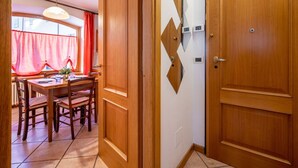 A wooden door with a geometric mirror design, a dining area with a table and chairs, and a hanging light fixture. - Nice apartment for 4 people with WIFI, TV and pets allowed (Prè-saint-didier)
