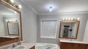 A bathroom with two sinks, a bathtub, and a window with blinds. - Beautiful Queen Room (Brampton)