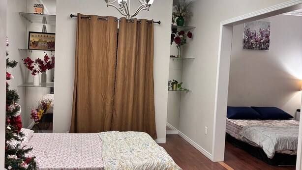 A bedroom with a bed, a chandelier, a Christmas tree, and a bathroom visible through an open door. - Beautiful Queen Room (Brampton)