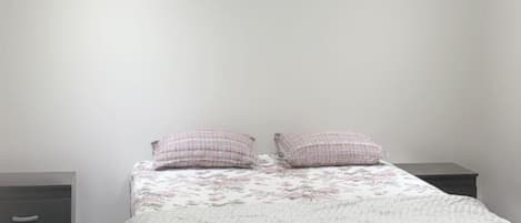 A bedroom with a bed, a ceiling fan, and a nightstand.