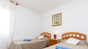 A hotel room with two beds, each with a wooden headboard, a small bedside table with a lamp, and a framed picture on the wall. - Stunning private villa for 6 guests with private pool, A/C, TV, patio and pets allowed (L'almadrava)