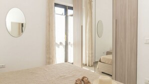 A bedroom with a bed, a mirror, a wardrobe, and a door leading to another room.