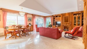 Un amplio salón con comedor, muebles de madera, un sofá rojo y un televisor.