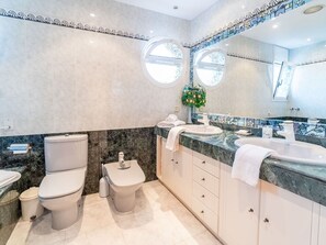 A modern bathroom with two toilets, a bidet, a sink with a mirror, and a decorative plant. - Stunning private villa for 8 people with A/C, WIFI, TV and patio (Pineda De Mar)