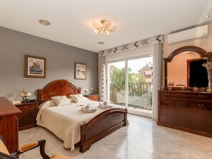 A bedroom with a large bed, a dresser, a desk, and a balcony with a view of buildings. - Stunning private villa for 8 people with A/C, WIFI, TV and patio (Pineda De Mar)