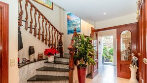 Una imponente escalera de mármol con barandilla de madera y una gran planta en maceta.