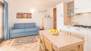 Un espace de vie compact comprenant un canapé, une table à manger avec des chaises, un coin cuisine avec une cuisinière et un réfrigérateur.