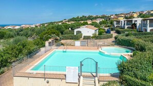 Un complexe hôtelier doté d’une grande piscine, entouré d’une végétation luxuriante et offrant une vue sur une ville côtière.