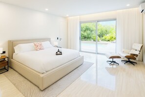 A modern bedroom with a large bed, a side table, a chair, and a view of a swimming pool. - 2 rooms with private pool | Villa 2 (Pigeon-Pea Hill)
