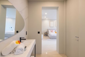 A modern hotel room with a large mirror, a white sink, and a neatly made bed. - 2 rooms with private pool | Villa 2 (Pigeon-Pea Hill)