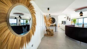 A modern interior with a large mirror, a reception desk, and a view of the outdoors. - Apartment in Estepona - Boho Chic - Ojala Casa (Estepona)