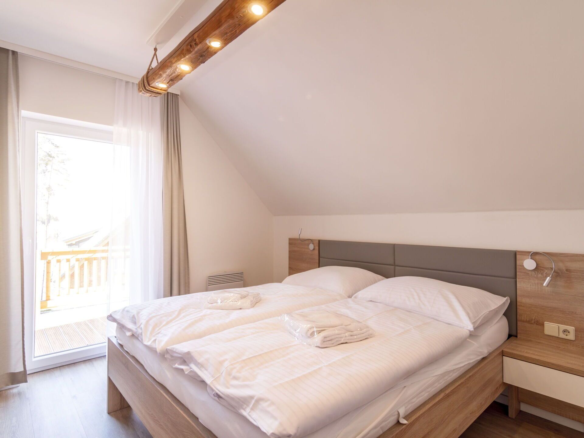 A modern bedroom with a large bed, a wooden headboard, bedside tables, and a ceiling light fixture.