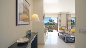 A modern hotel room with a large window, a dining area with a table and chairs, and a living area with a sofa and a coffee table. - Nice apartment for 6 guests with pool, A/C, WIFI, TV and terrace (Quarteira)