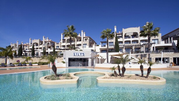 A hotel with a pool, palm trees, and a sign for 'LILY'S'. - Nice apartment for 6 guests with pool, A/C, WIFI, TV and terrace (Quarteira)