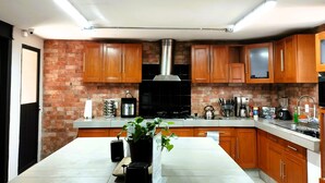 A modern kitchen with wooden cabinets, a central island, and a brick accent wall.