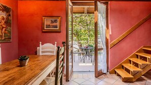 A dining area with a wooden table and chairs, a painting, and a view of an outdoor patio with a staircase. - Beautiful apartment for 4 guests with hot tub, WIFI, TV, balcony and pets allowed (Vendrogno)