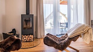Un salon moderne avec un poêle à bois, un fauteuil confortable et une vue sur l’extérieur.