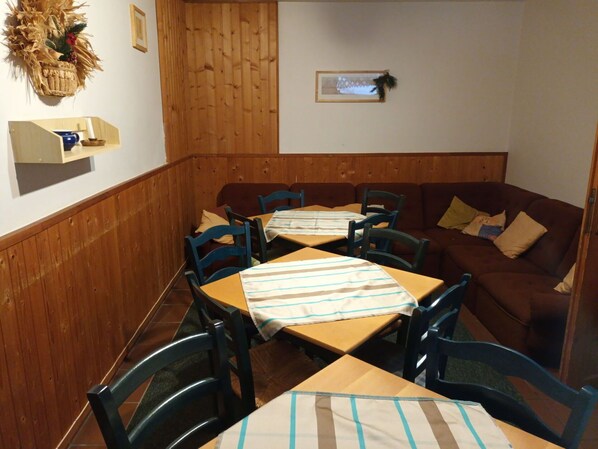 Ein gemütliches Restaurant mit Holzwandverkleidung, einem braunen Sofa und Tischdecken mit Streifen.