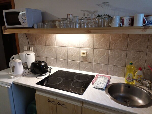 A kitchen with a microwave, toaster, kettle, and a sink.