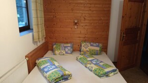 A small, cozy room with a wooden headboard, a window with blinds, and a door. - Nice apartment for 12 people with WIFI and pets allowed (Jilemnice)