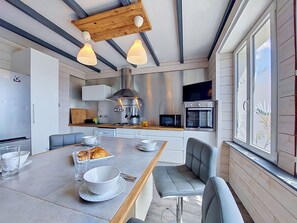 A modern kitchen with a central island, built-in appliances, and a large window.