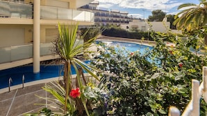 A multi-story hotel with a swimming pool surrounded by lush greenery and palm trees.
