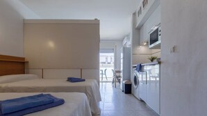 Ein Hotelzimmer mit zwei Betten, einer Waschmaschine und einer Küchenzeile.
