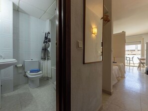 A bathroom with a toilet, sink, and shower curtain. - Cosy apartment for 3 people with A/C, WIFI, pool and terrace (Salou)