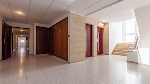 Ein geräumiger Flur mit Fliesenboden, Holztüren und einer Treppe, die in einen oberen Bereich führt.