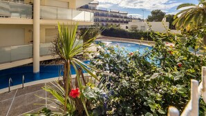 Ein mehrstöckiges Hotel mit Schwimmbad, umgeben von üppiger Vegetation und Palmen.