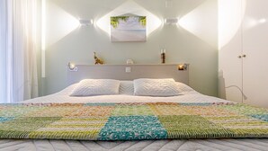 Una cama bien hecha con un colcha colorida, un cabecero con luces empotradas en la pared y un pequeño objeto decorativo en la estantería.