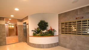 Un hall d’entrée avec un comptoir de réception, un escalier et un panneau indiquant l’emplacement « BAJOS ».