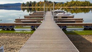 A wooden pier extending into calm water with docked boats and a forested shoreline in the background. - Beautiful private villa for 10 people with WIFI, TV and terrace (Lojzova Paseka)