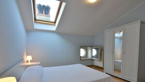 Una camera da letto con un lucernario, un letto, un armadio e un comodino con una lampada.