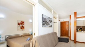 Et moderne hotelværelse med to senge, en sofa, et lille bord og et tekøkken.