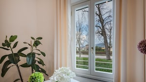 Una habitación con ventana, planta en maceta y un jarrón con flores.