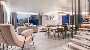 A modern living room with a pool view, a dining area, and a kitchen.