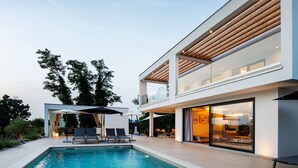 A modern house with a swimming pool, outdoor seating, and large windows.
