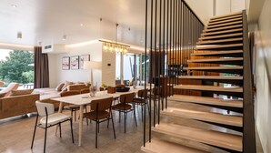 A modern interior with a dining area, a staircase, and a living room.