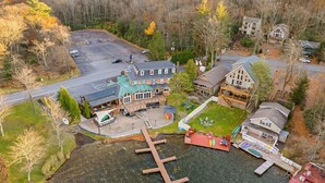 An aerial view of a lakeside property with a main building, dock, and surrounding forest. - Walk to Town-Lake Views-6 Decks-Pool Table-FirePit: The Lookout (Lake Harmony)