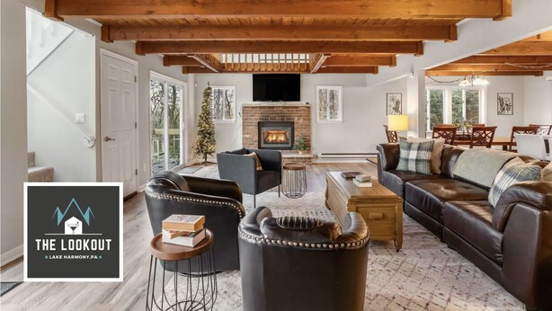 A spacious living room with a fireplace, leather furniture, and a wooden ceiling. - Walk to Town-Lake Views-6 Decks-Pool Table-FirePit: The Lookout (Lake Harmony)